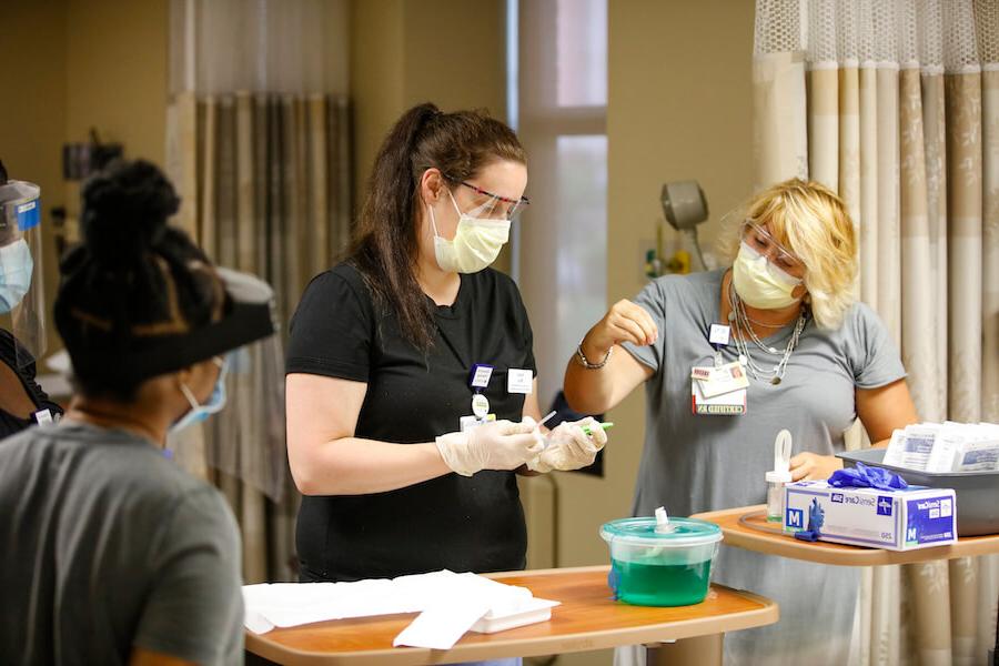 A University of Rochester 护理学院 student is being taught how to handle medical equipment in a hospital setting.